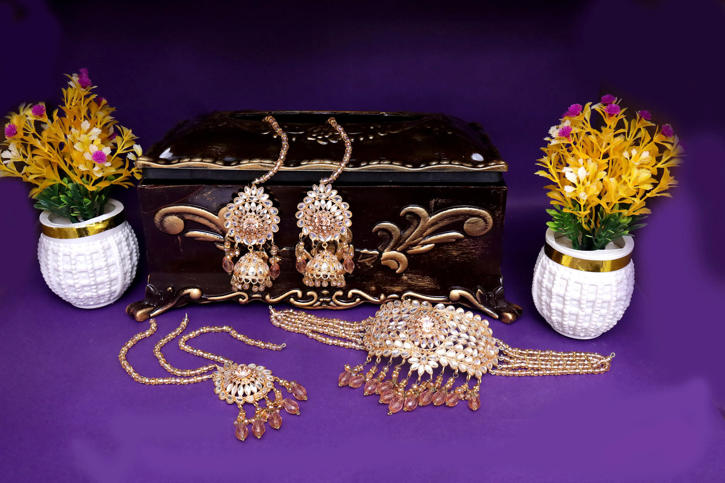 Gold jewelry set with decorative plants on a purple background
