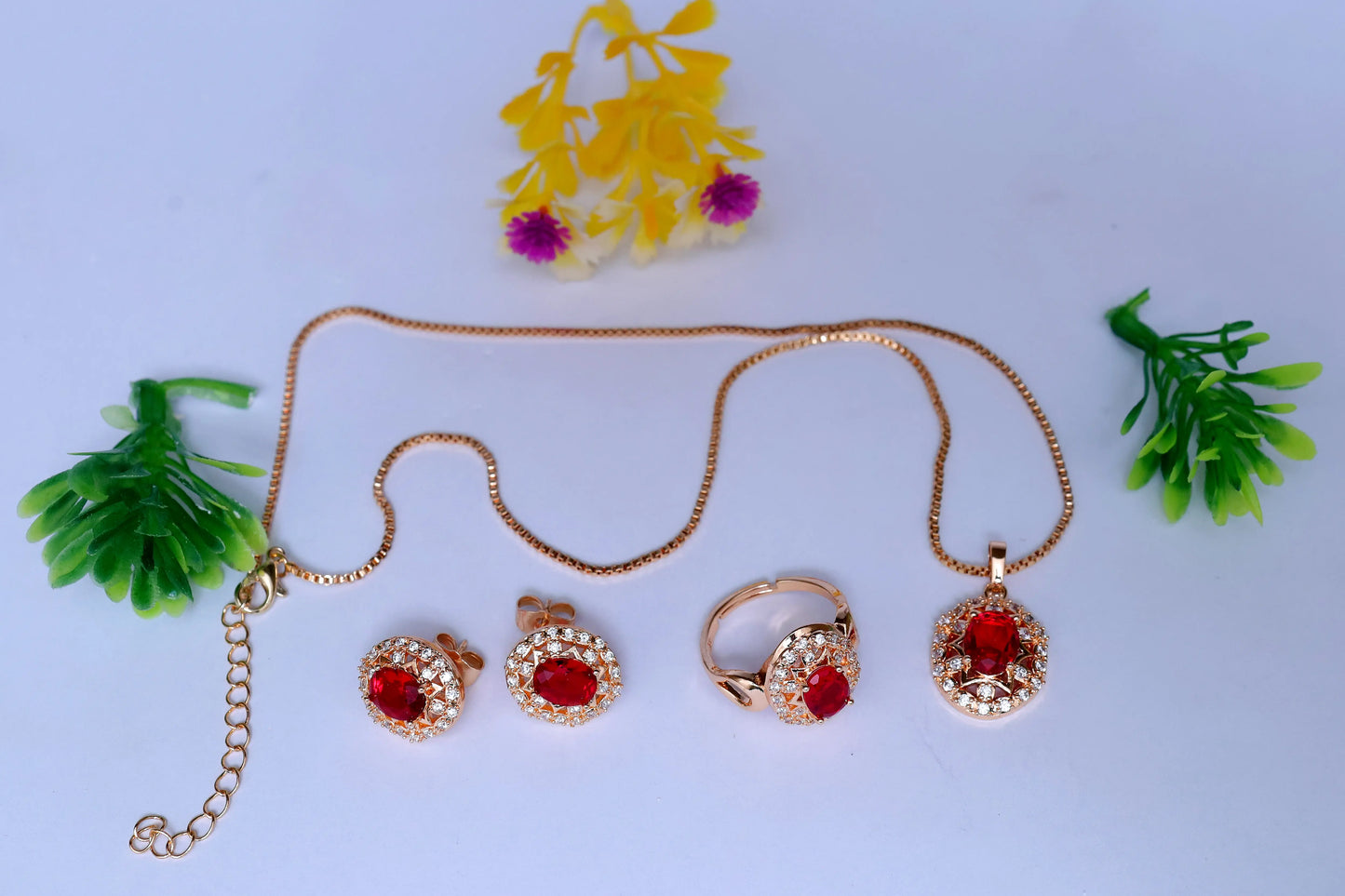 Gold jewelry set with red stones on a light blue background