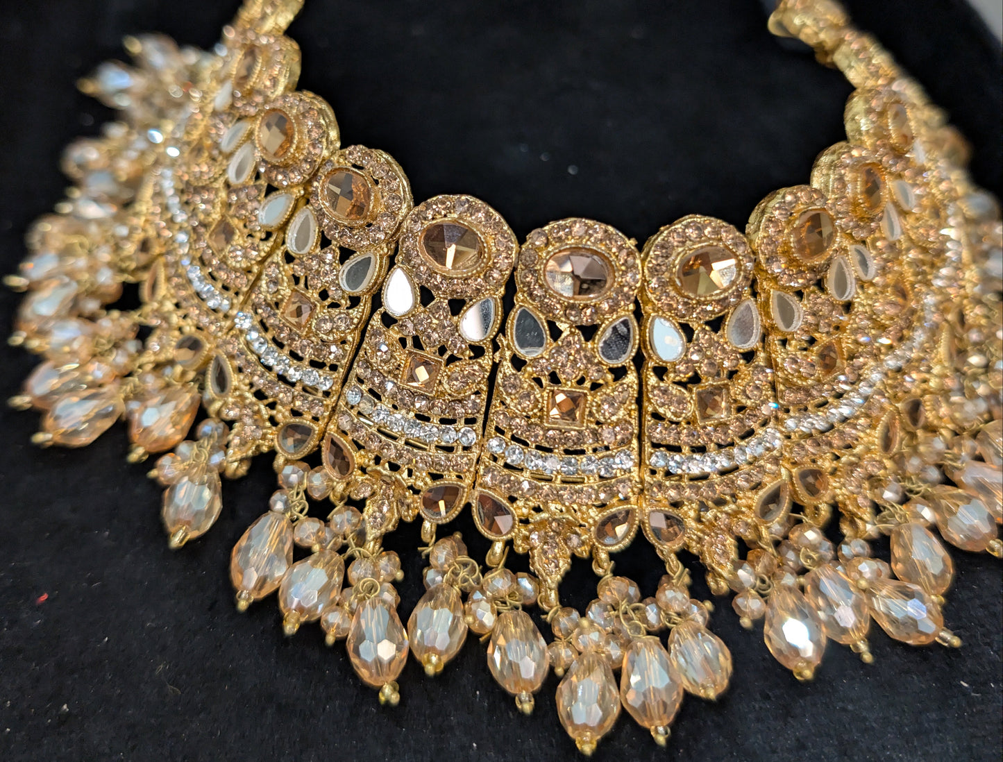 Gold necklace with intricate design on a black velvet surface