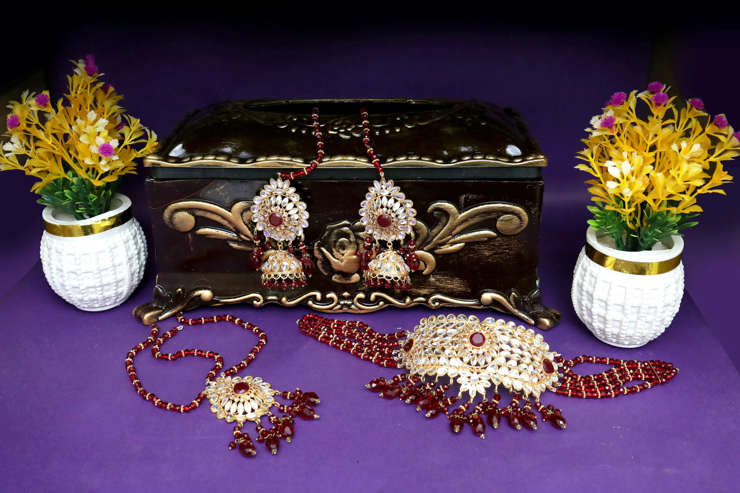 Jewelry set with earrings, necklace, and decorative box on a purple background
