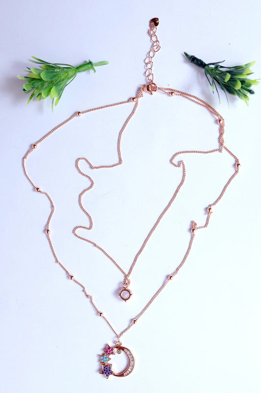 Rose gold necklace on a white background with green leaves