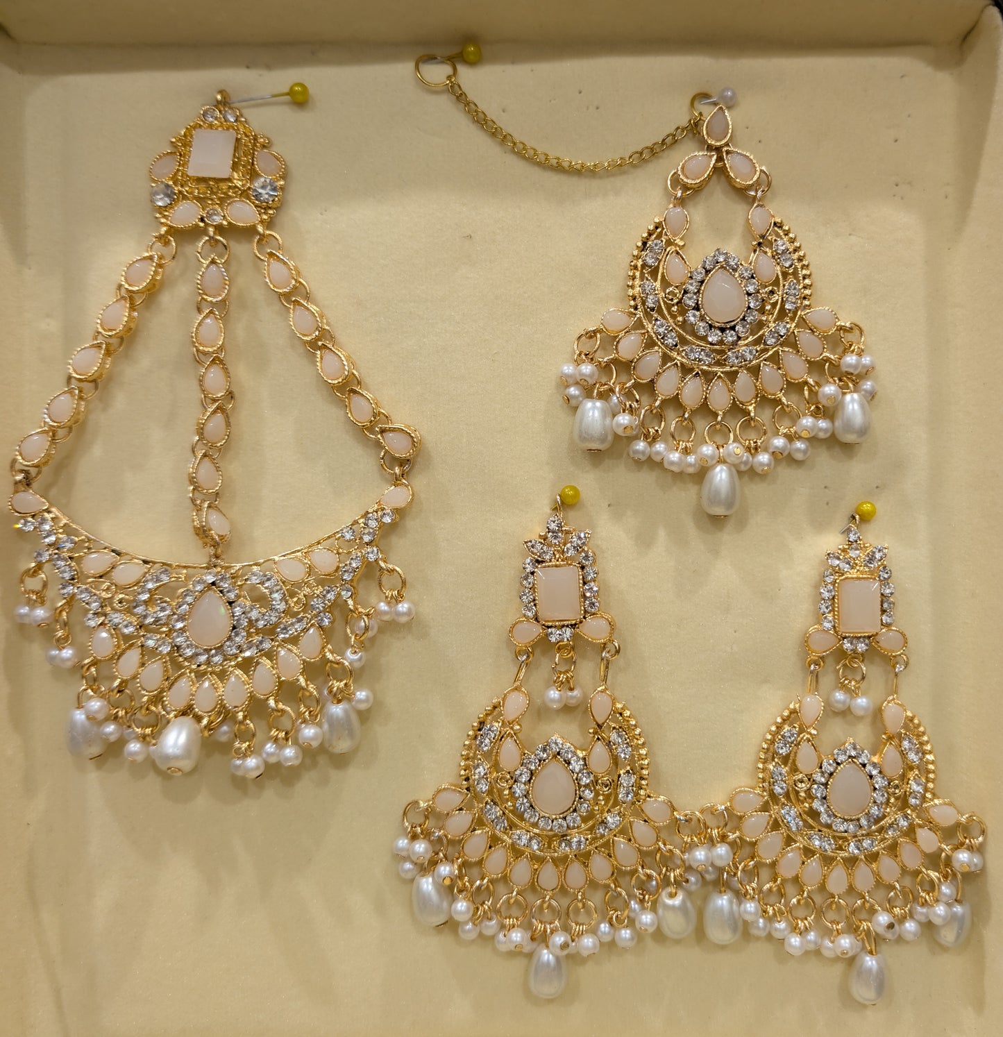 earrings, and matha patti on a beige background