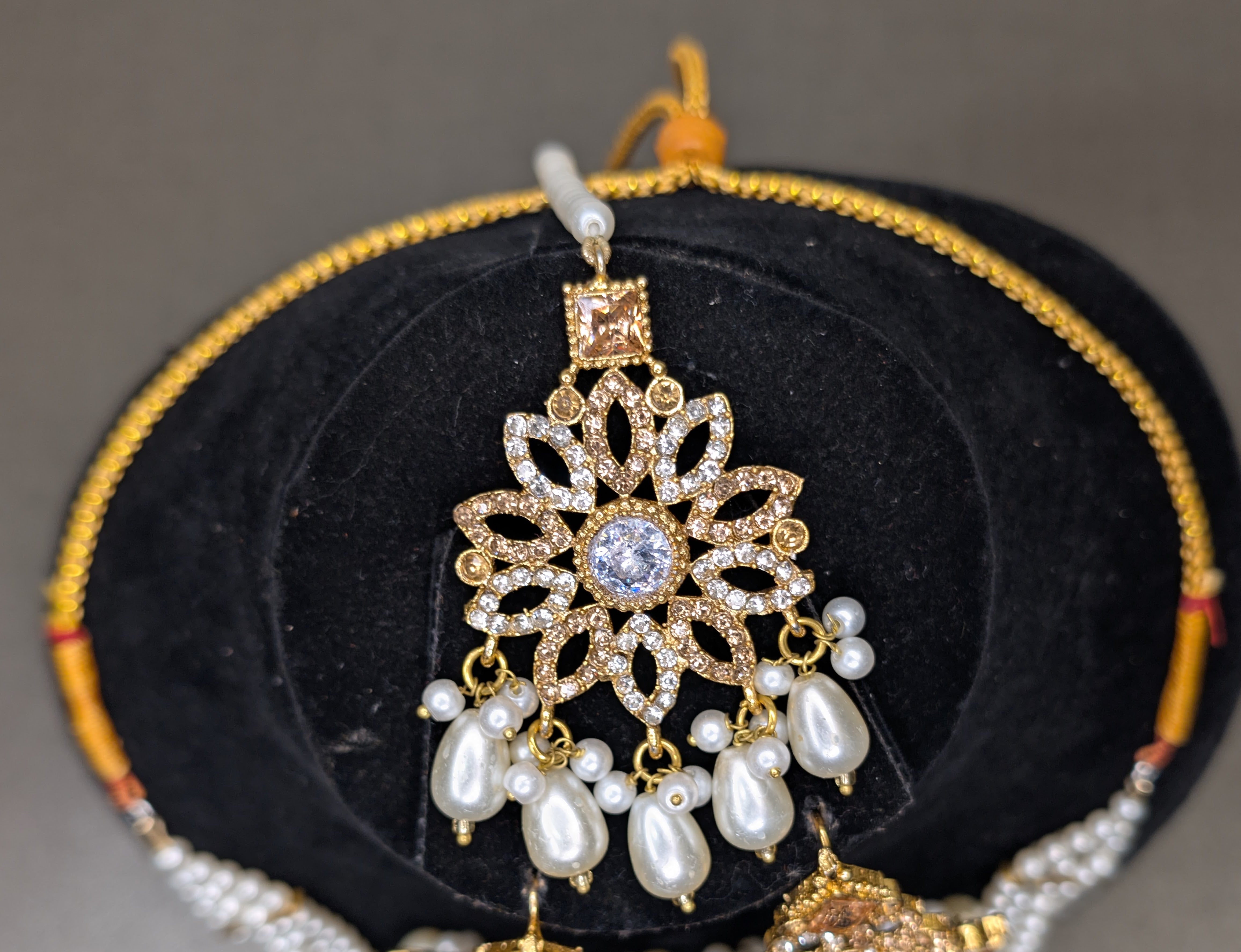 Decorative headset with pearls on a black cushion with gold trim