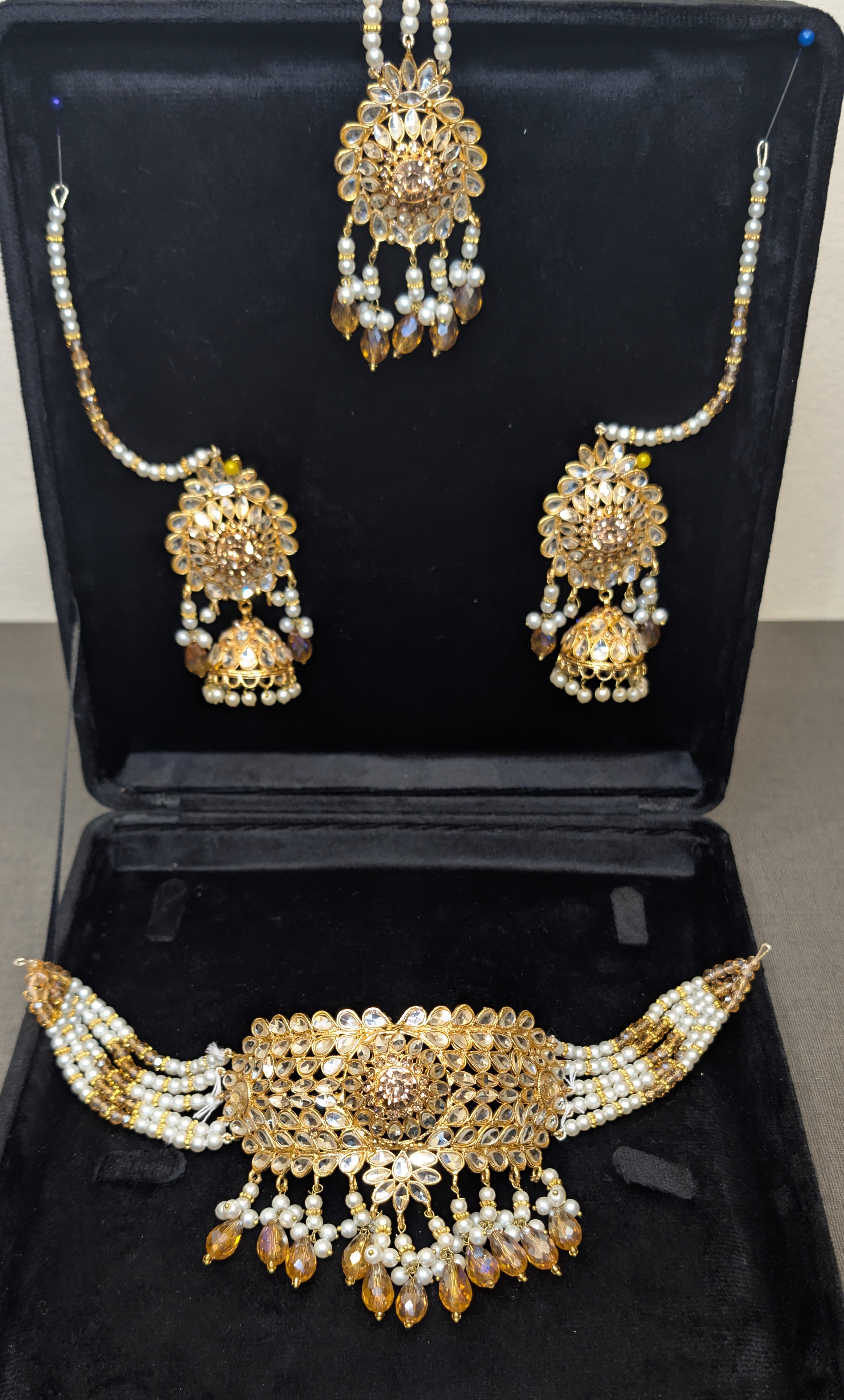 Gold and pearl jewelry set on a black stand