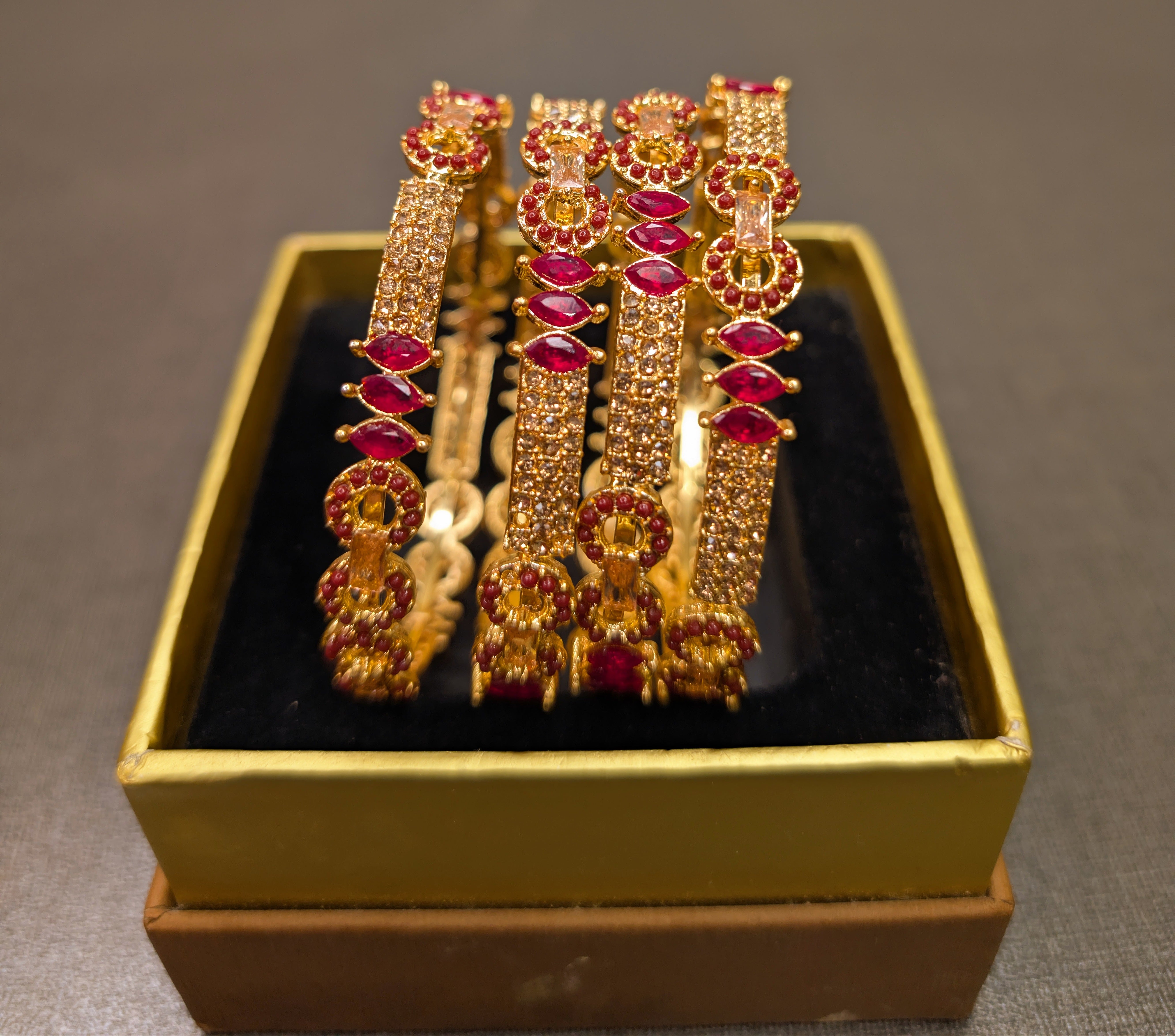 Gold and red gemstone jewelry set in a box on a gray background