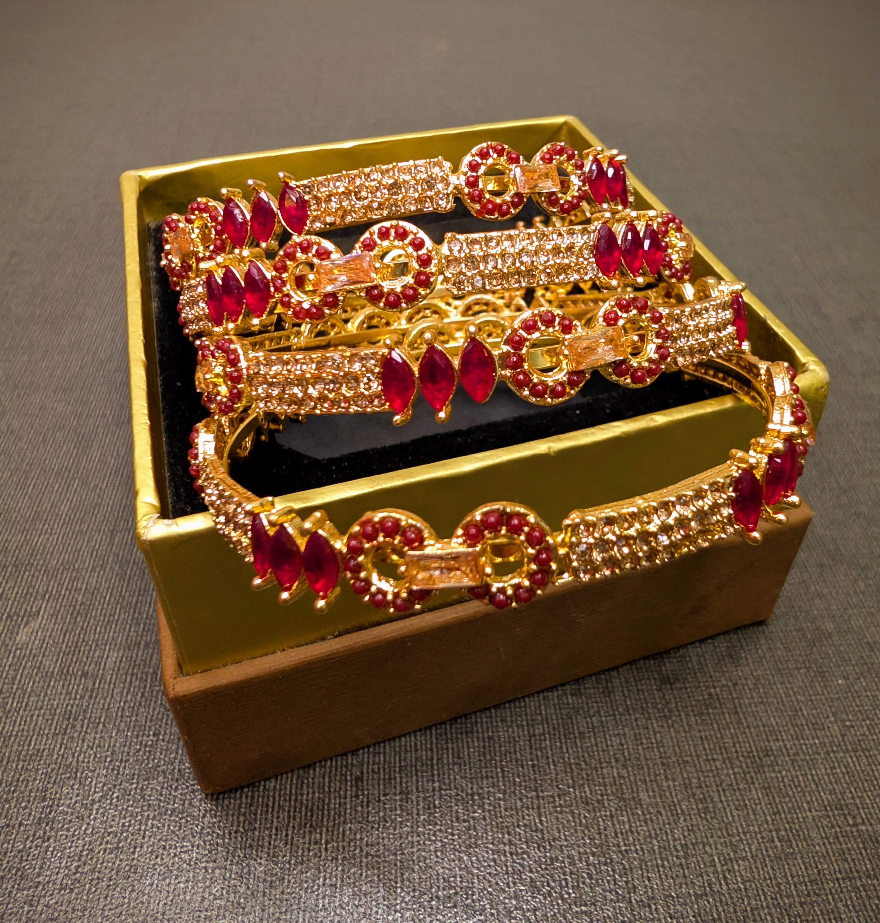 Gold and red jewelry set in a decorative box on a gray surface