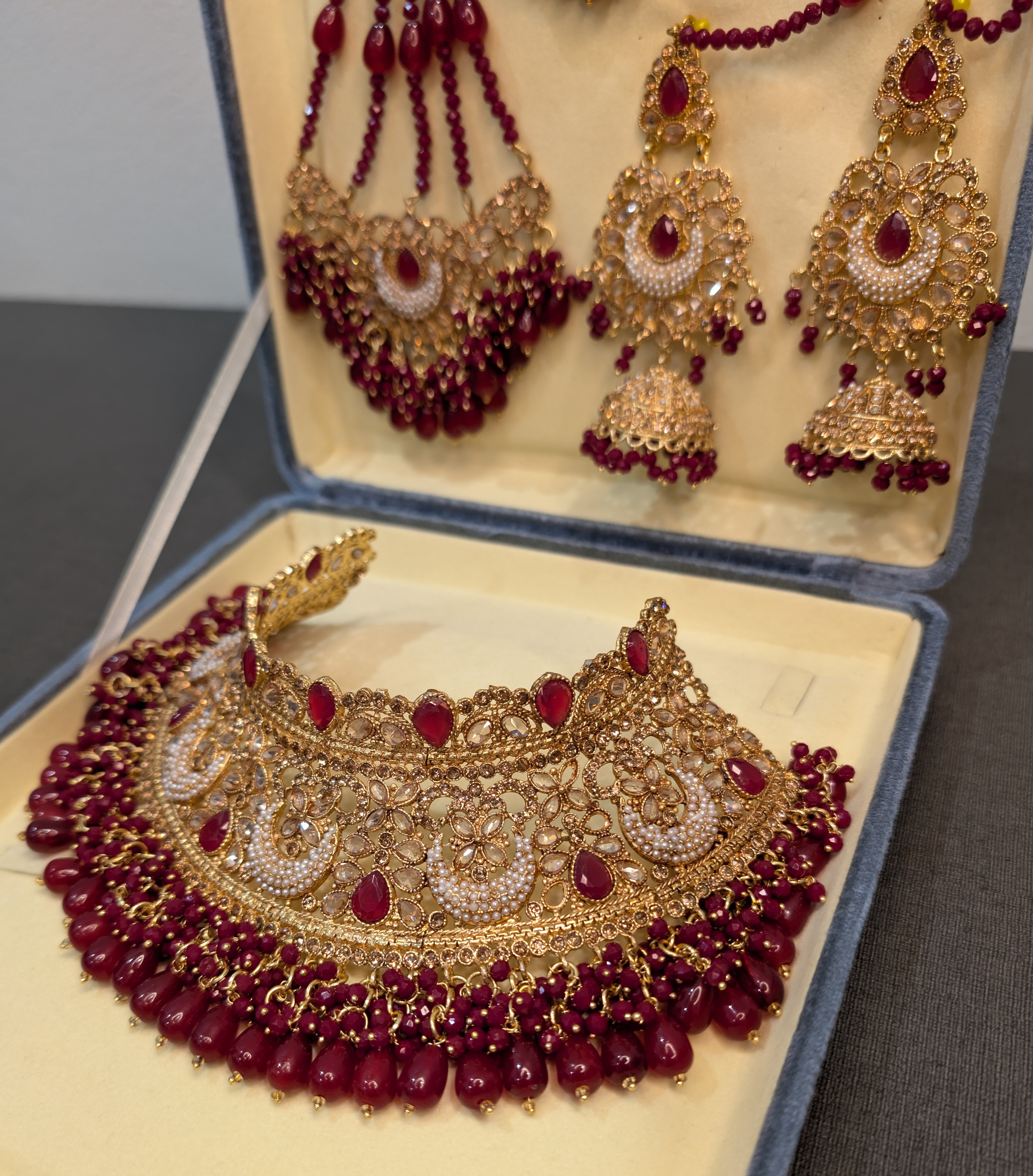 Gold and red jewelry set including necklace, earrings, and headband in an open jewelry box.