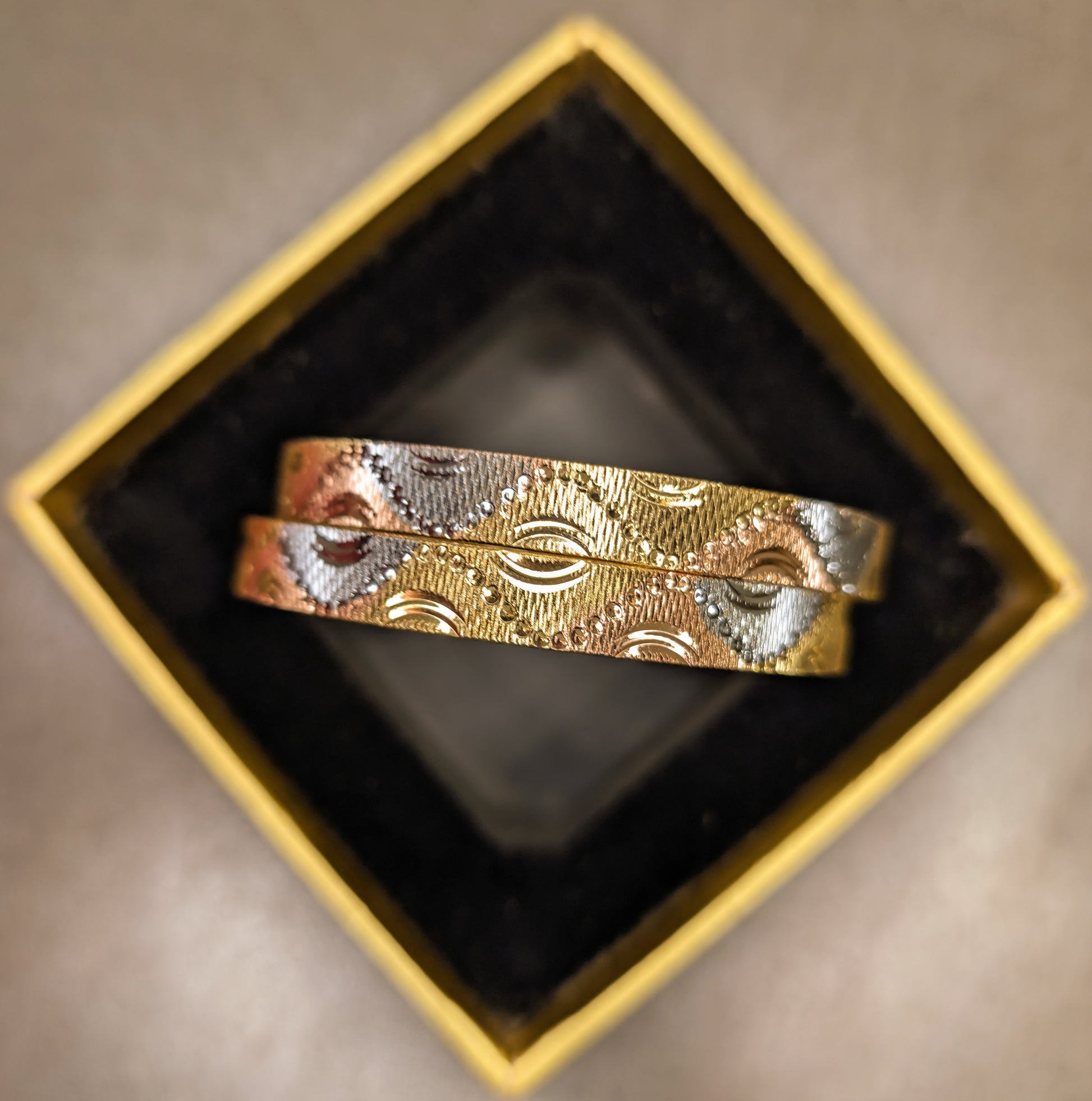 Gold and silver bracelet in a black box on a beige surface