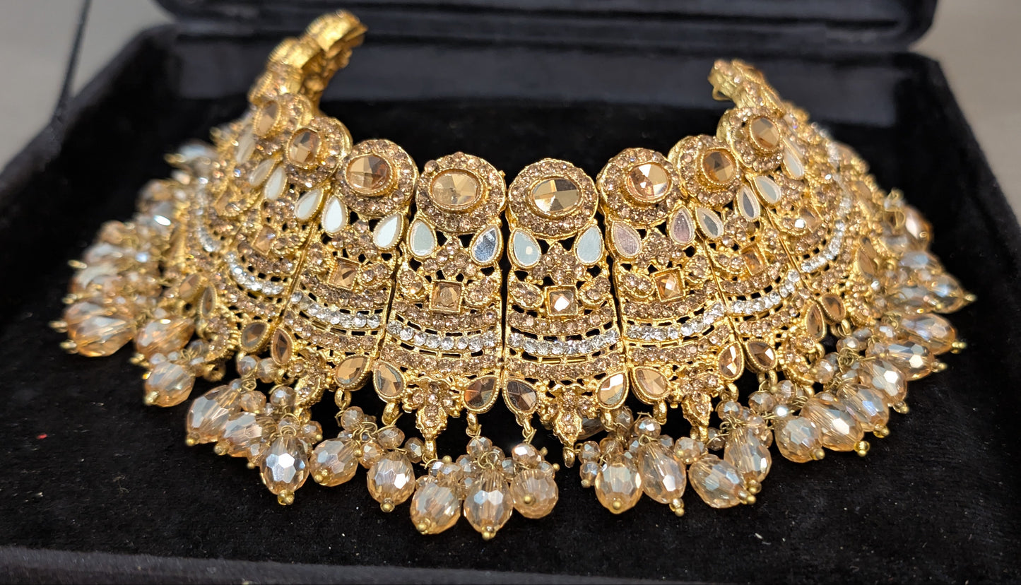 Gold jewelry set including necklace, earrings, and choker on a black display box.