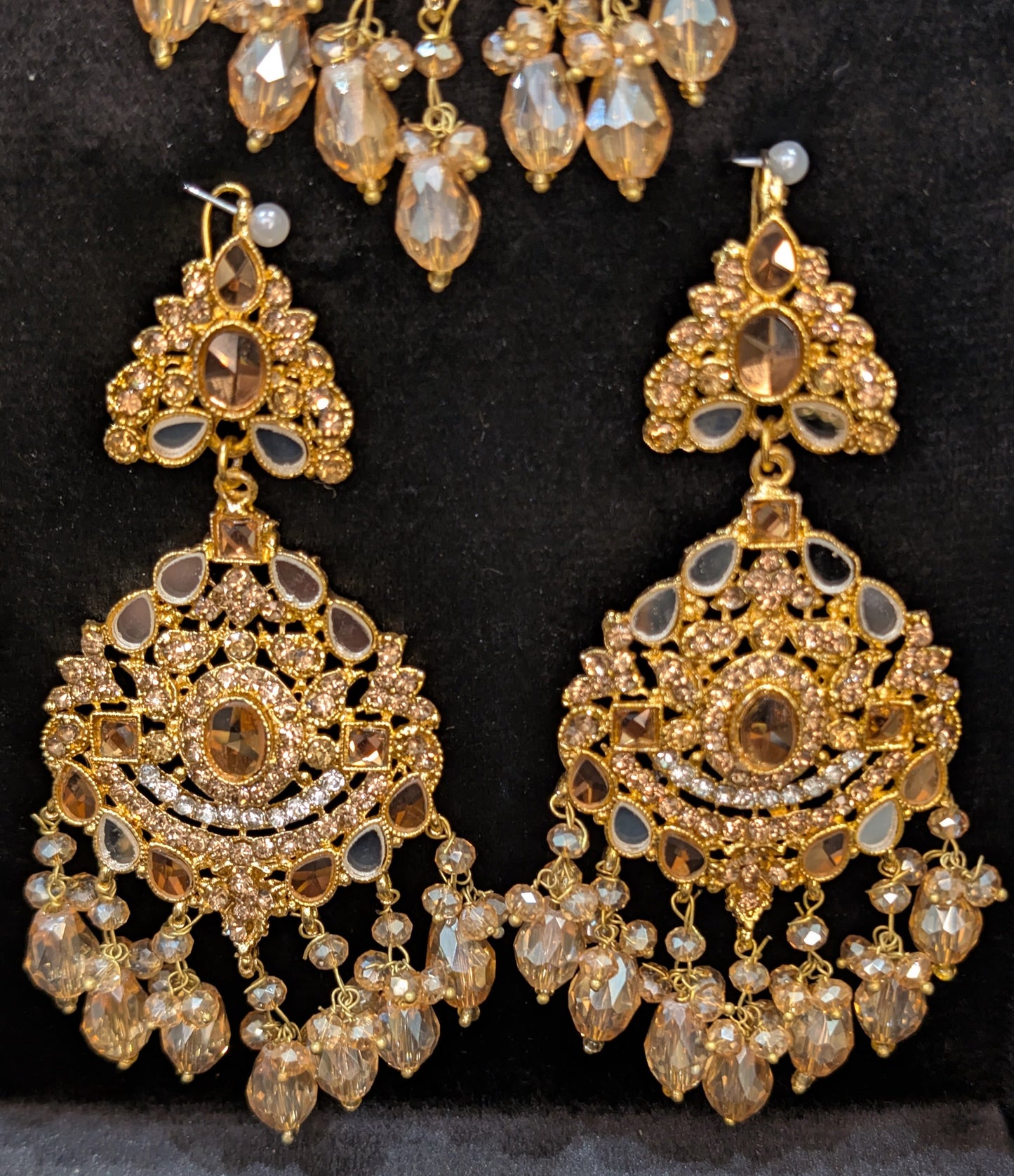 Gold jewelry set with earrings and necklace on a black background