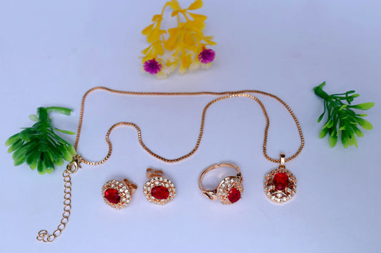 Gold jewelry set with red stones on a light blue background