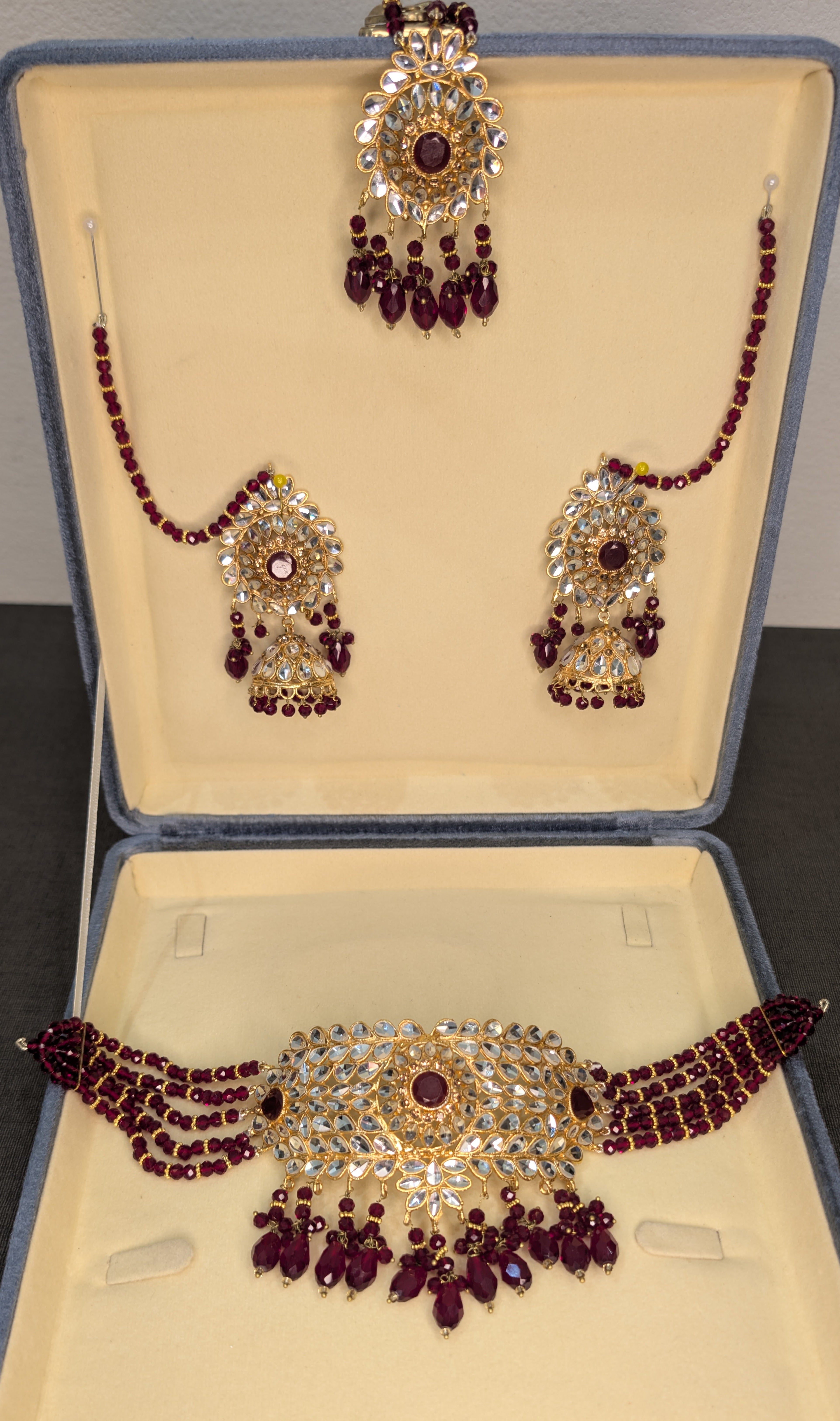 Gold necklace and earrings set on a black stand