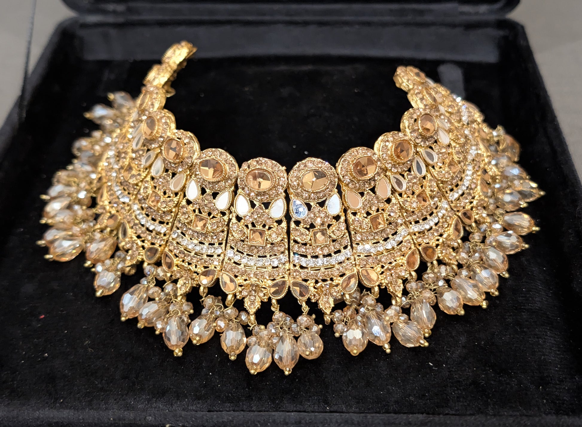 Gold necklace with intricate design on a black velvet background