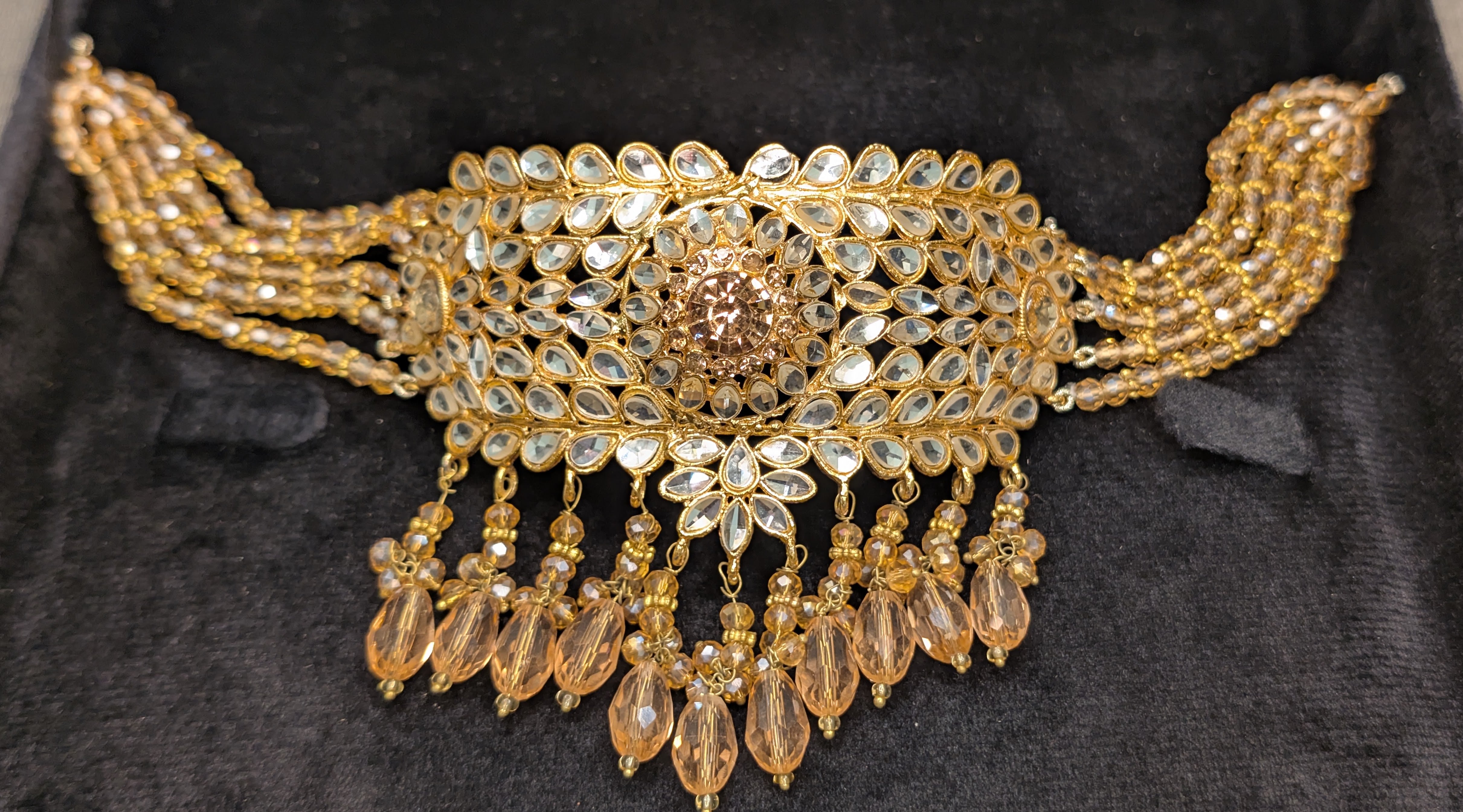 Gold necklace with intricate design on a dark background