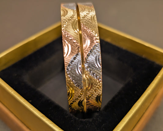 Gold ring with intricate design on a black cushion in a gold box