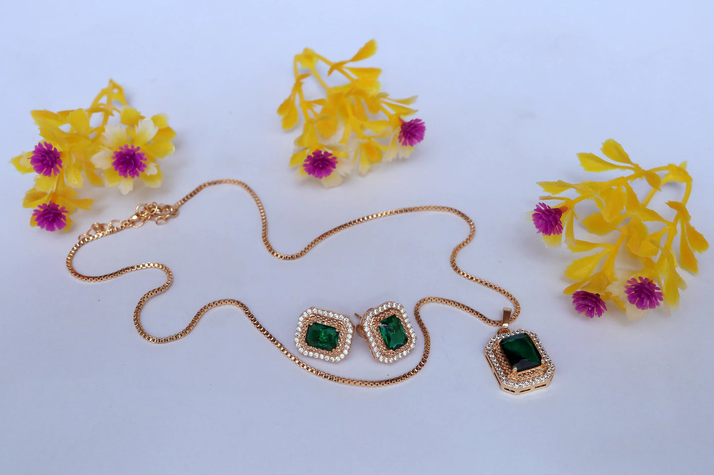 Jewelry set with green gemstones on a white background with yellow flowers.