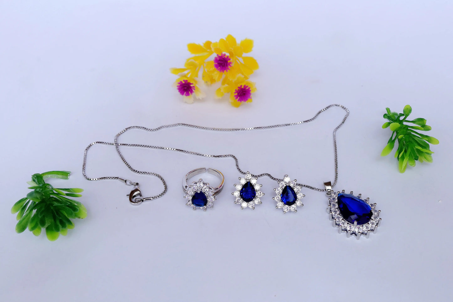 Jewelry set with necklaces and rings on a white background with decorative flowers and plants.