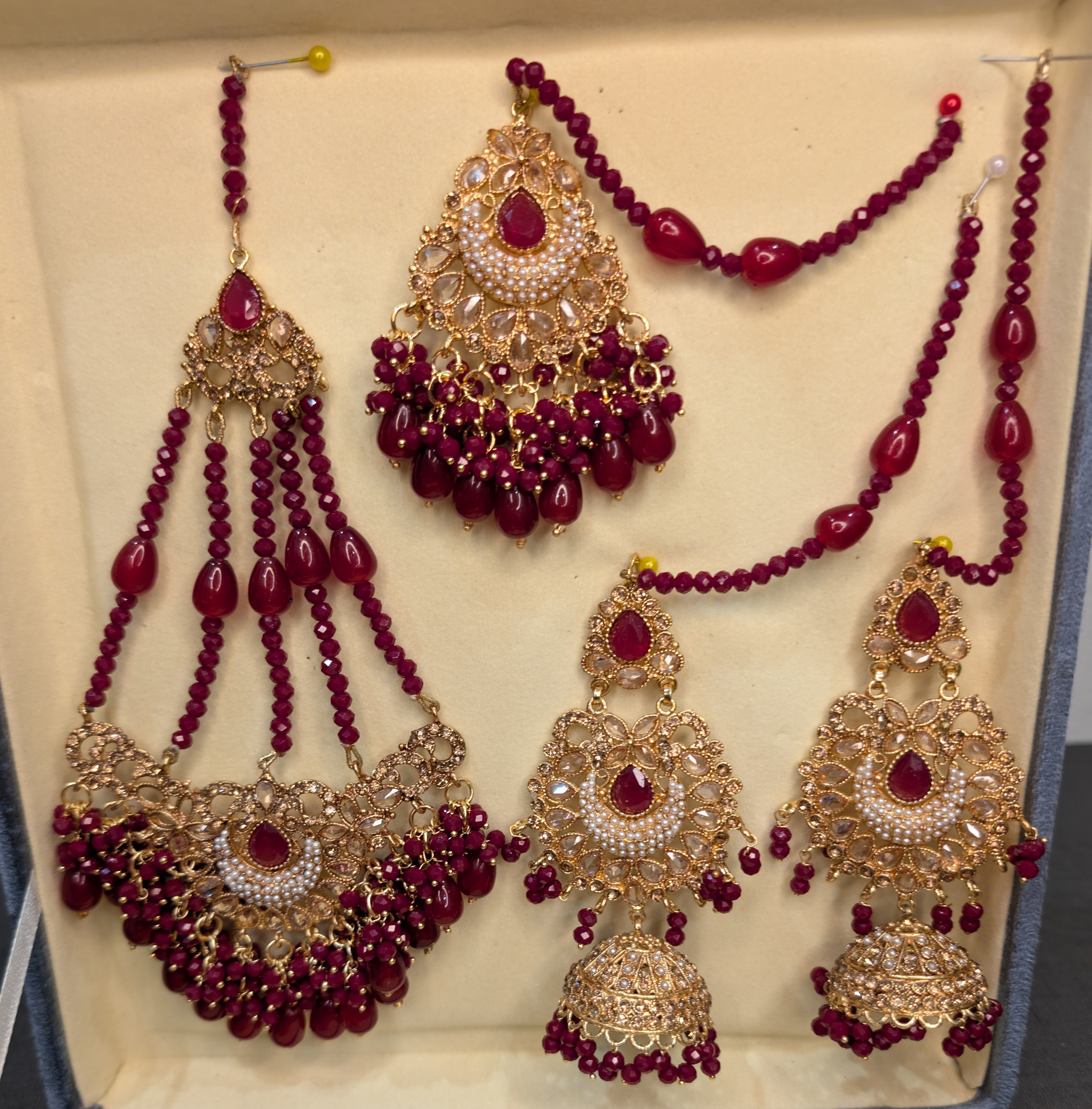 Jewelry set with red beads and gold accents on a beige background