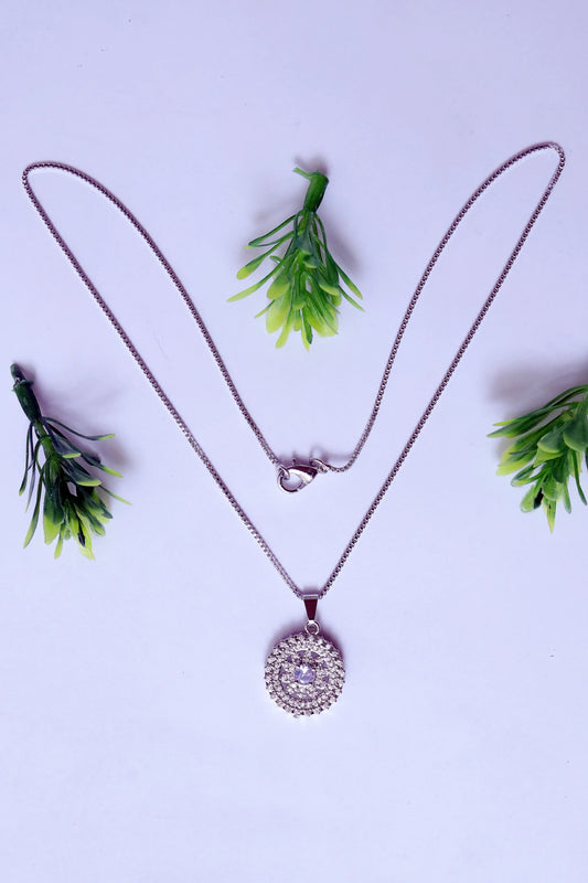 Necklace with a circular pendant on a light purple background with green leaves.