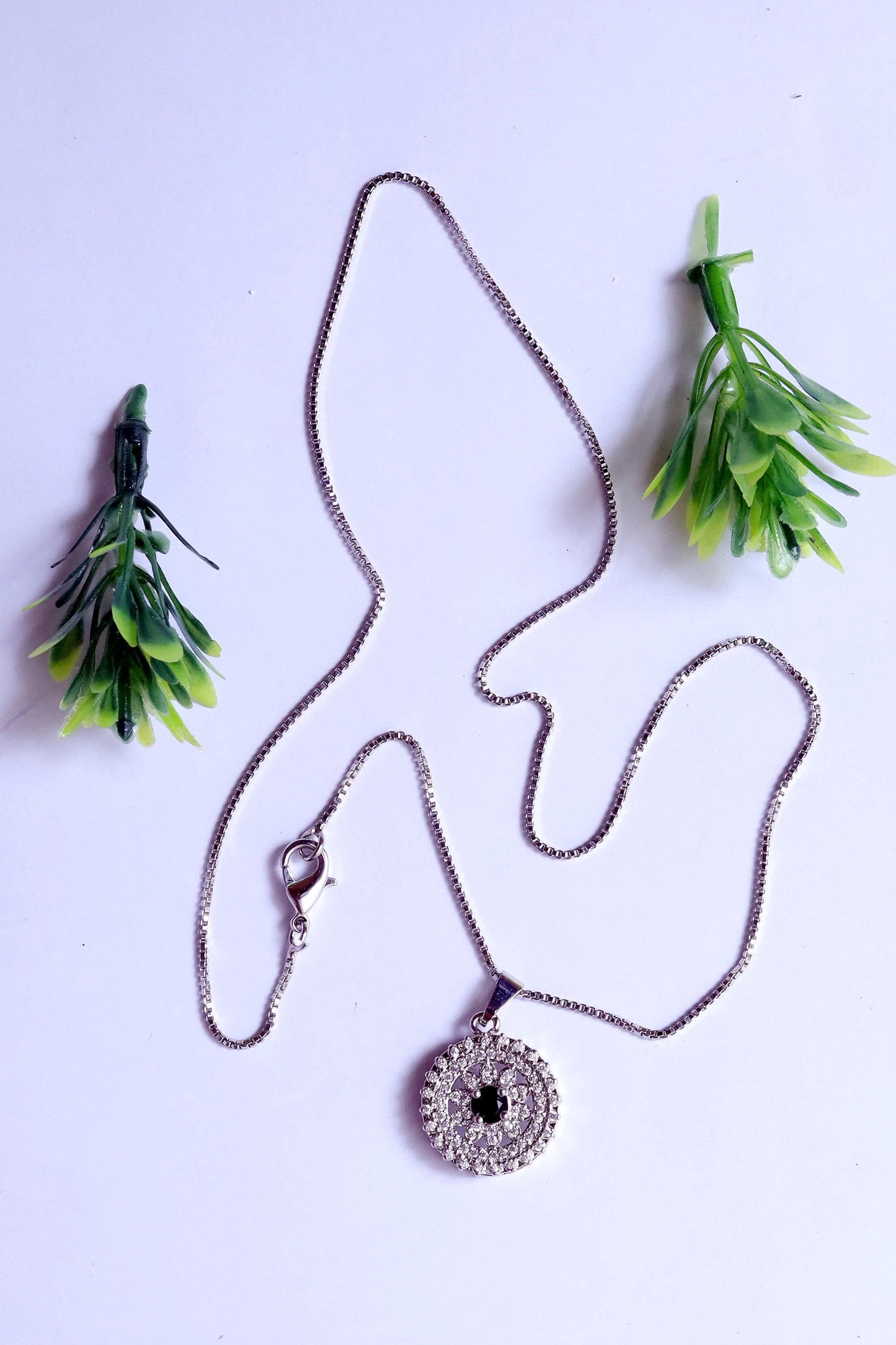 Necklace with a pendant on a white background with green leaves