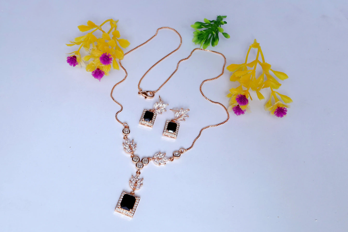 Necklace with pendant on a light blue background with decorative plants.