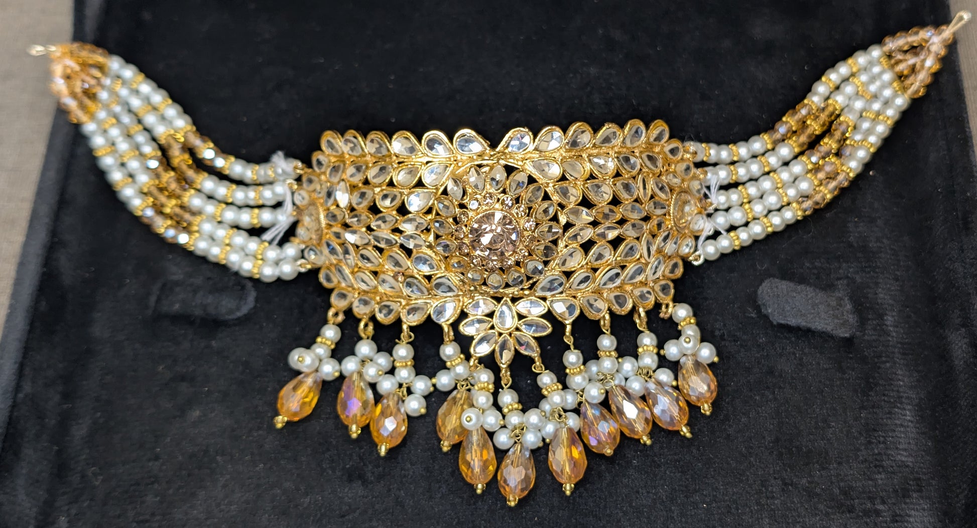 Ornate gold and pearl necklace on a black background