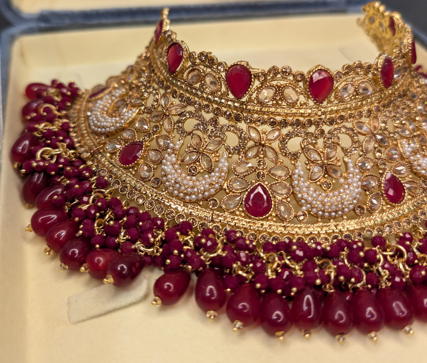 Ornate gold and red jewelry set on a beige background