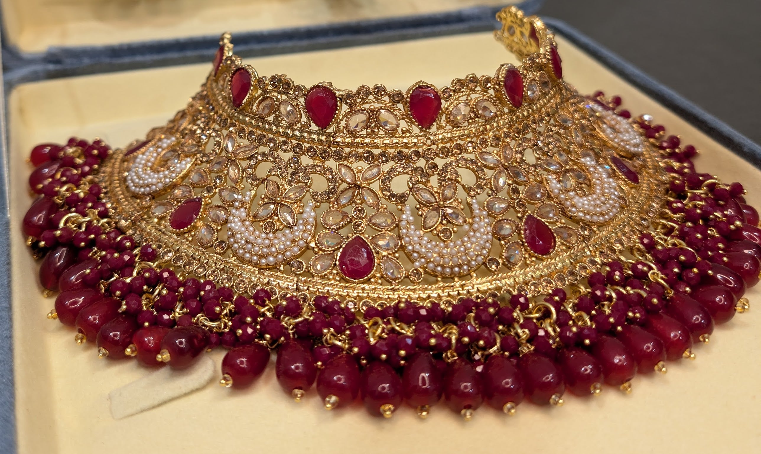 Ornate gold and red jewelry set on a beige background