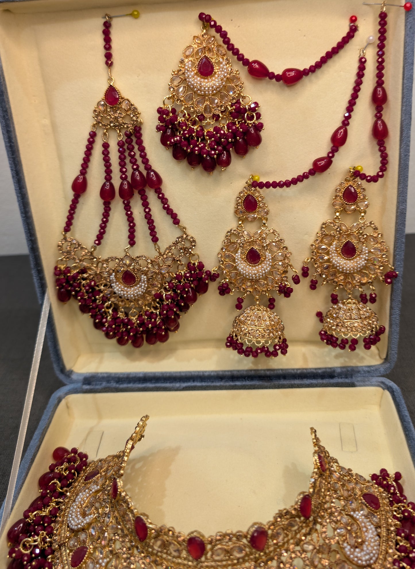 Ornate jewelry set with red beads and gold accents in a box
