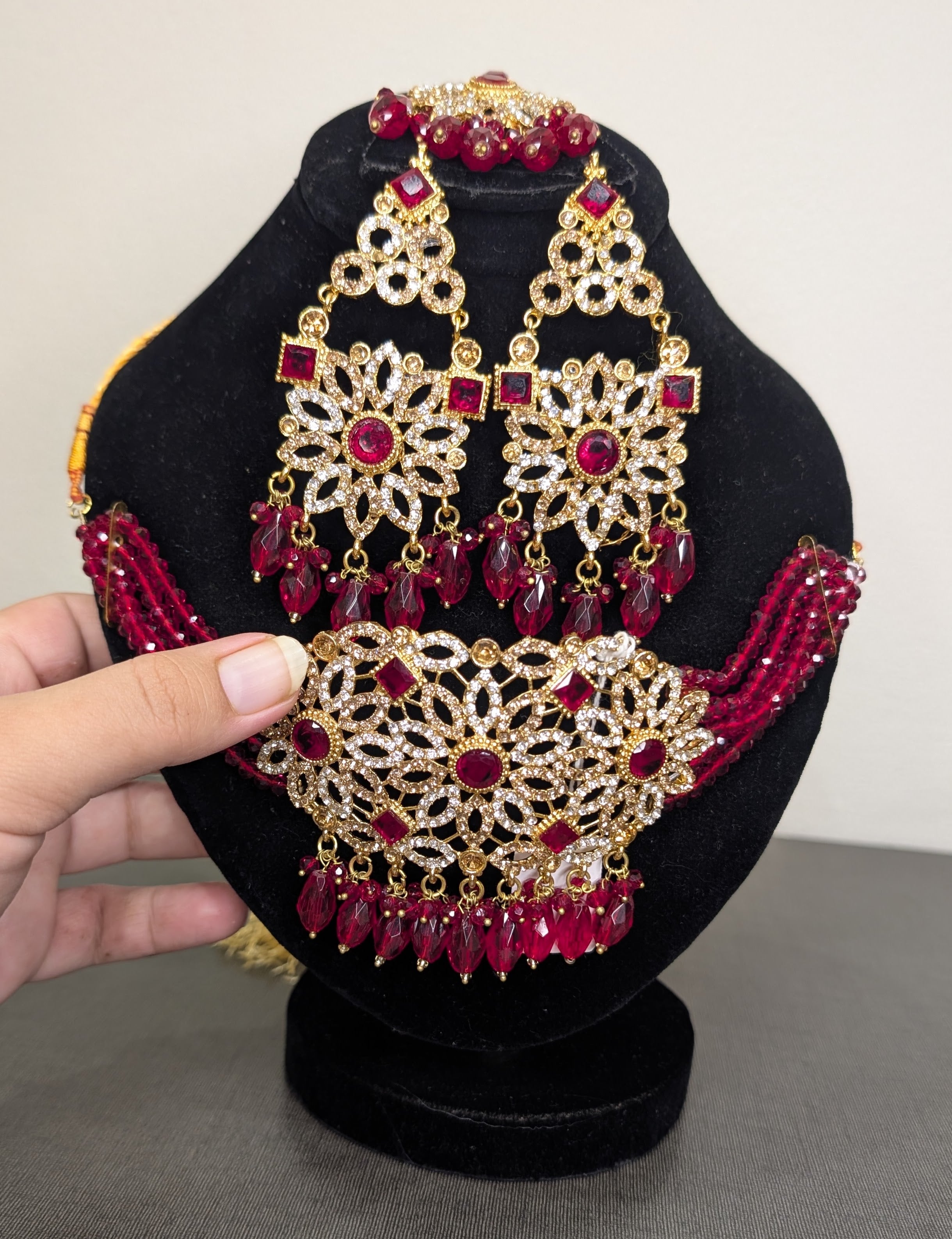 Ornate jewelry set with red stones on a black stand