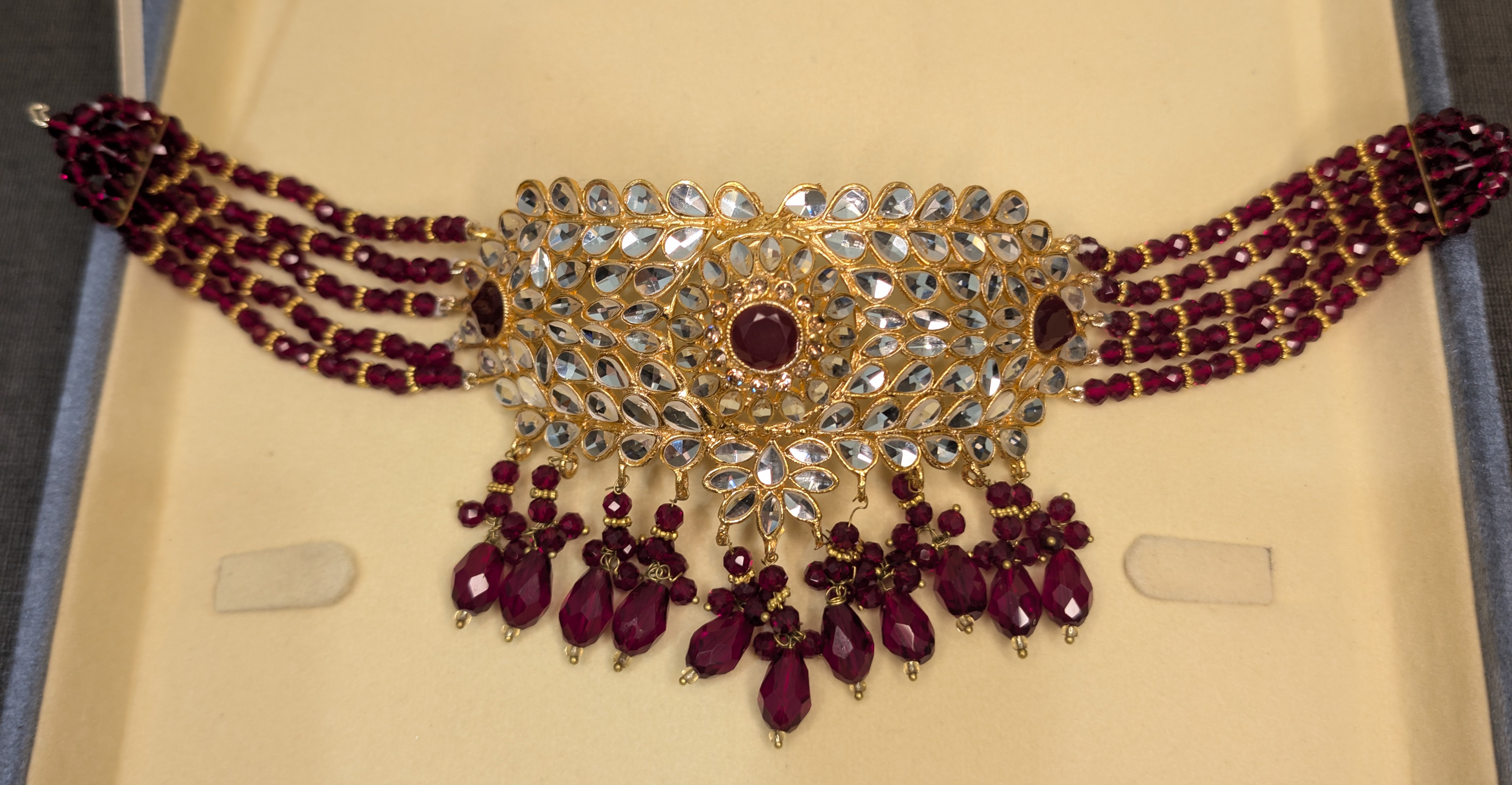 Ornate necklace with red gemstones on a beige background