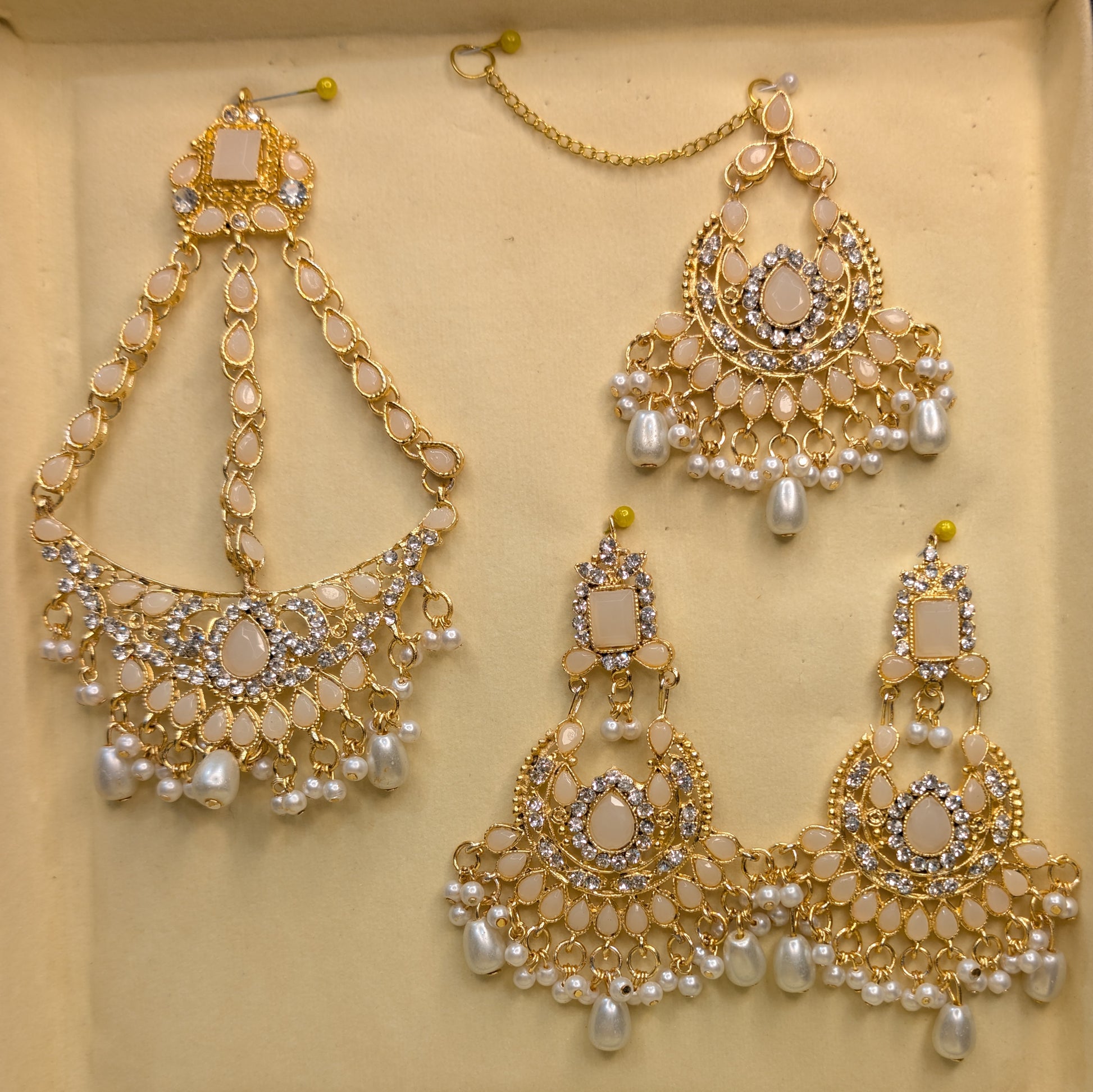 Set of gold and pearl jewelry on a beige background ear ring matha pati with hair set