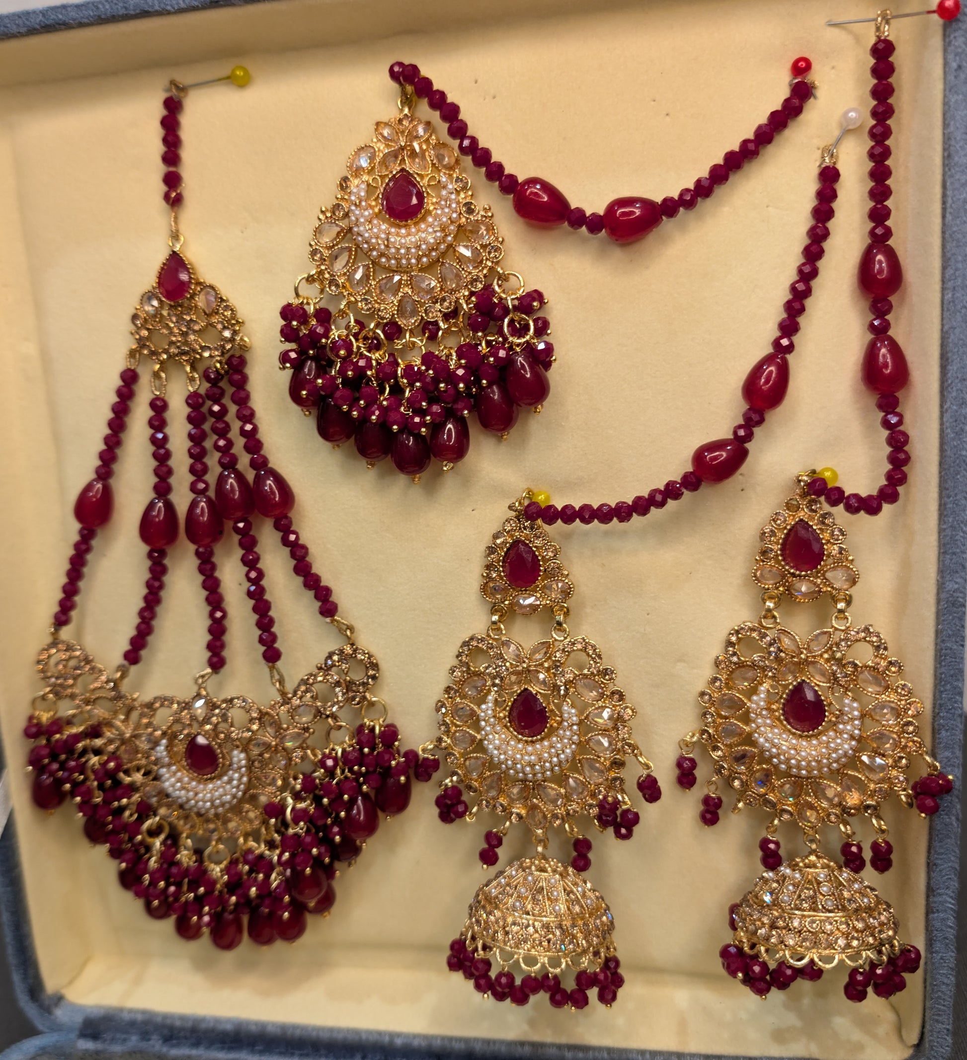 Set of gold and red beaded jewelry including necklace, earrings, and haram on a light background.