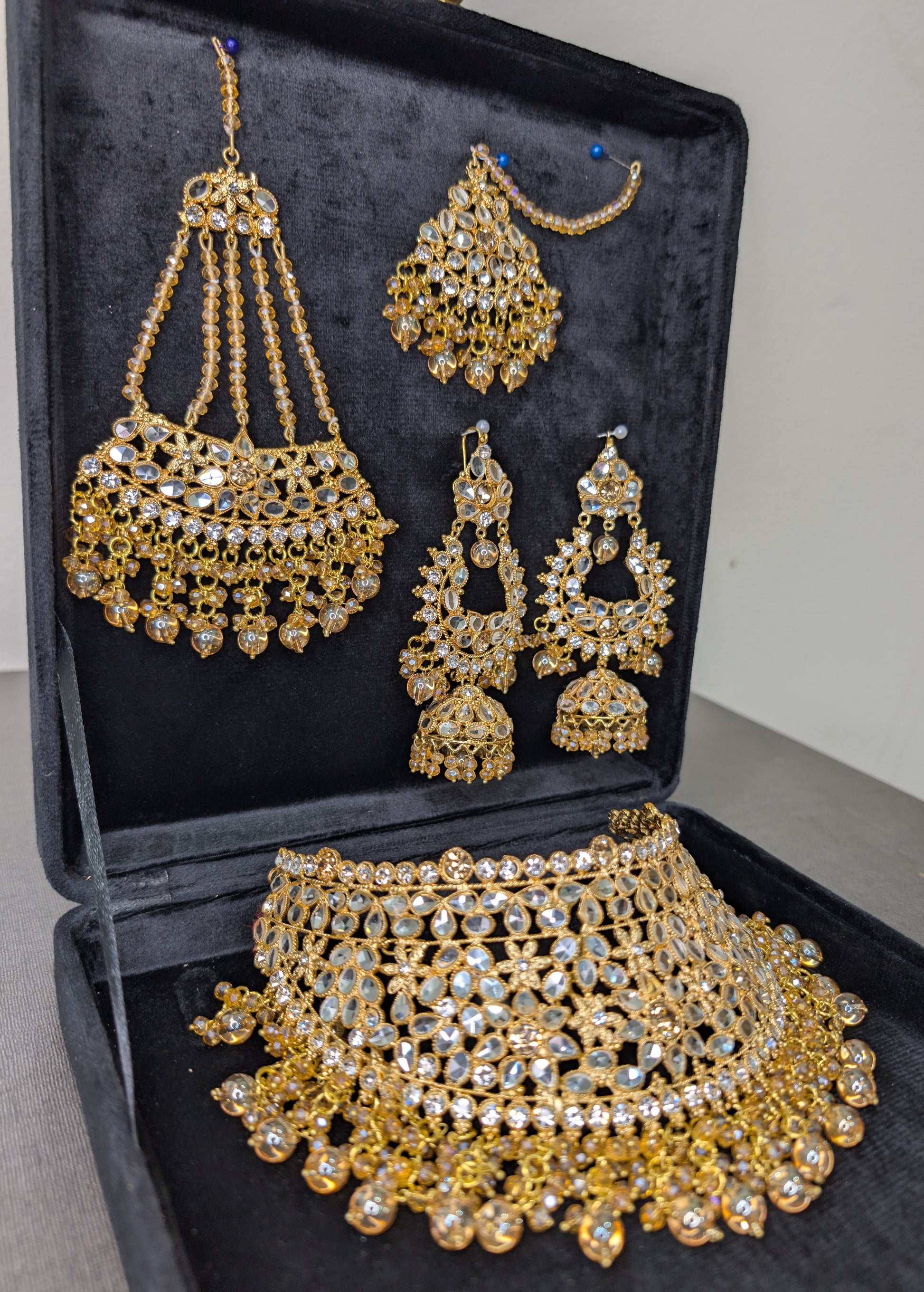 Set of gold jewelry including necklace, earrings, and choker in a black box.