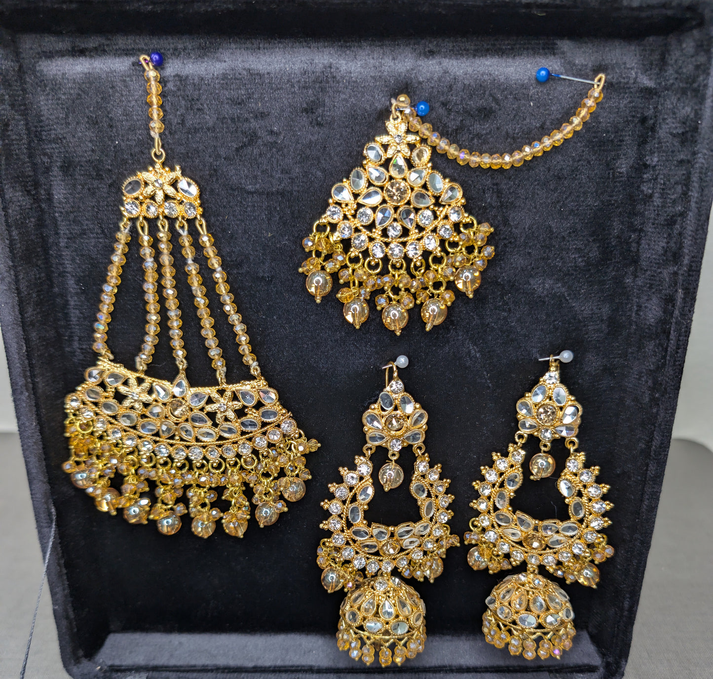Set of gold jewelry with intricate designs on a black background