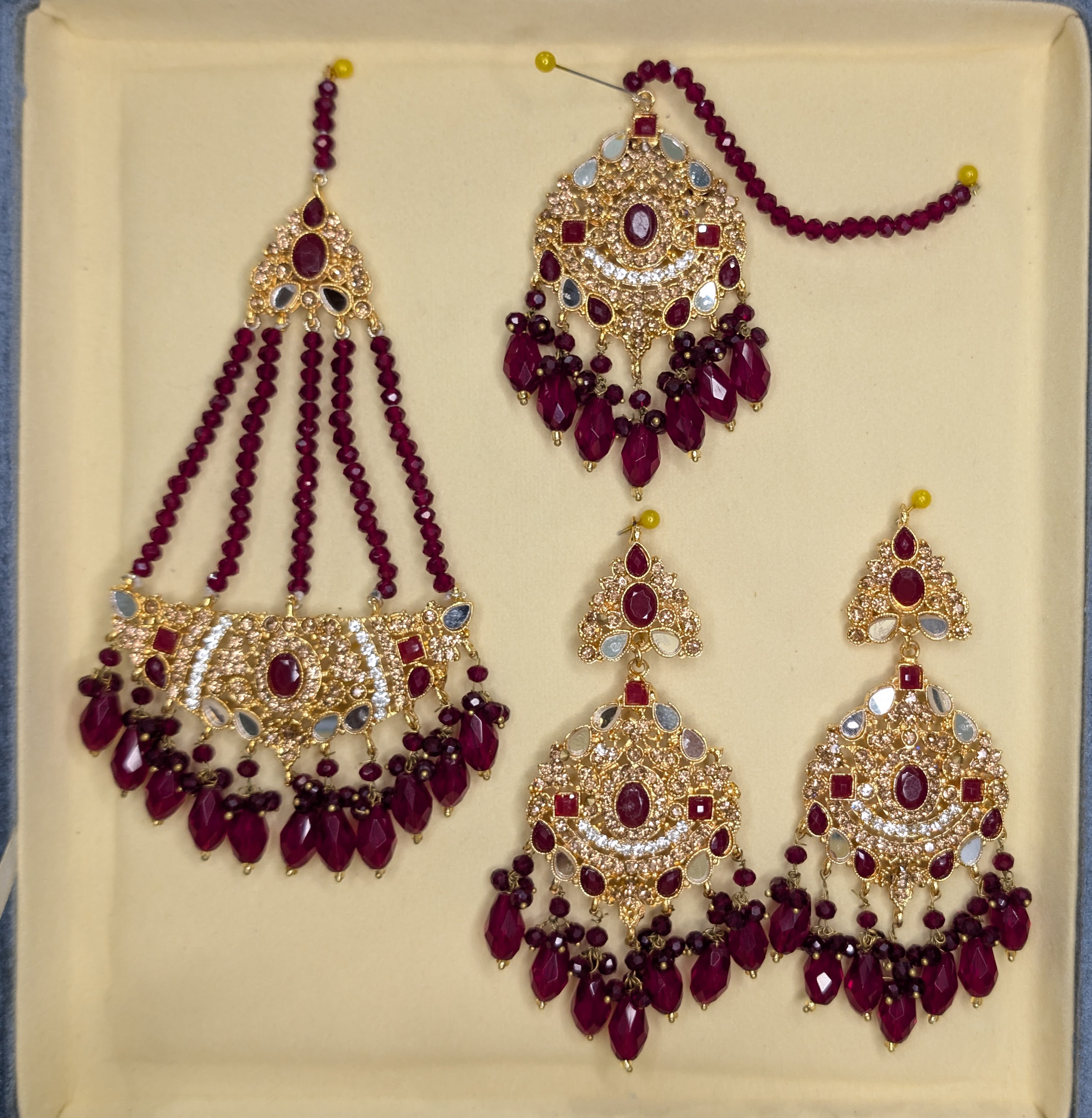 Set of ornate jewelry with red beads on a beige background