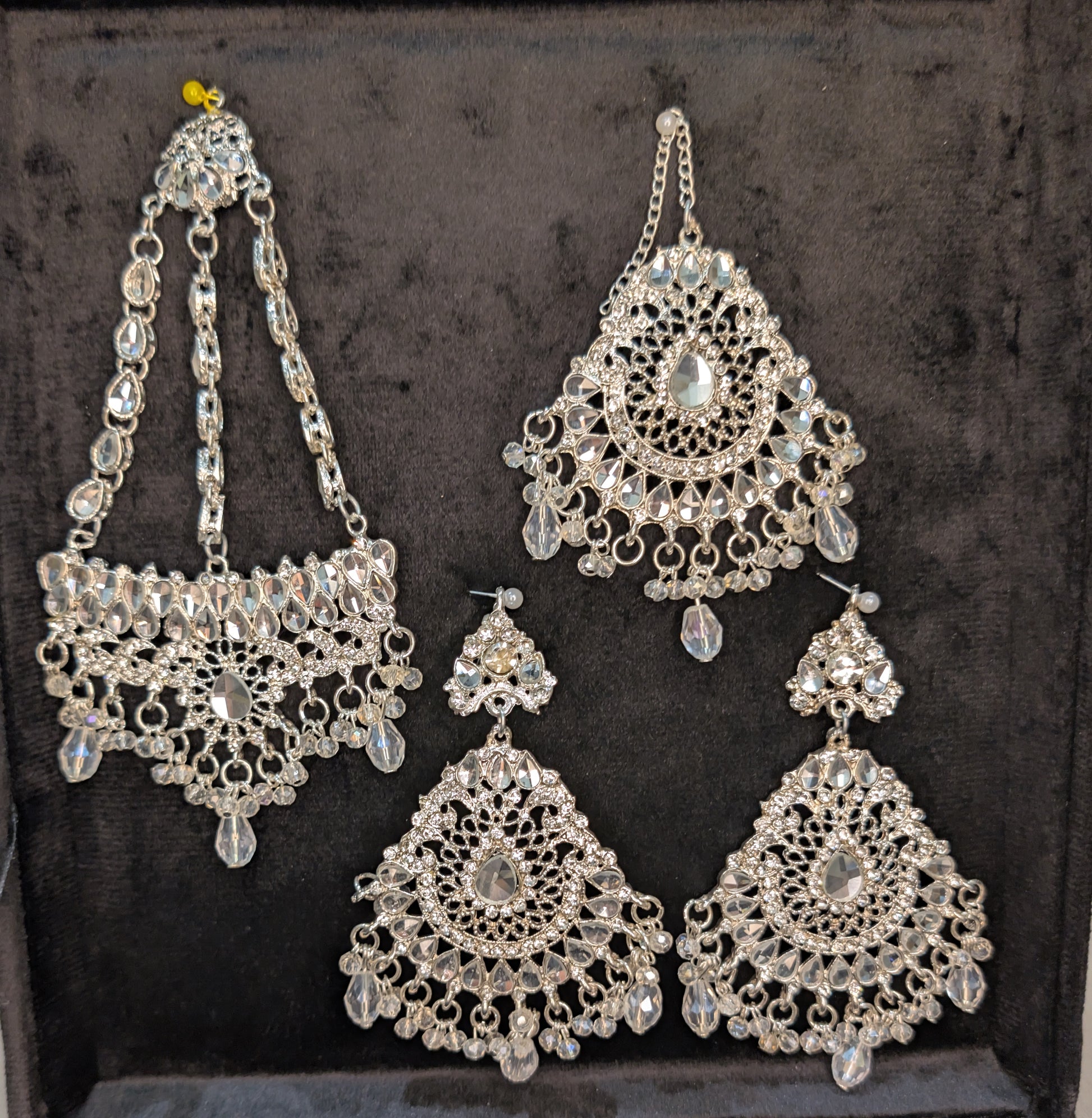 Silver jewelry  earrings, and head set on a dark background