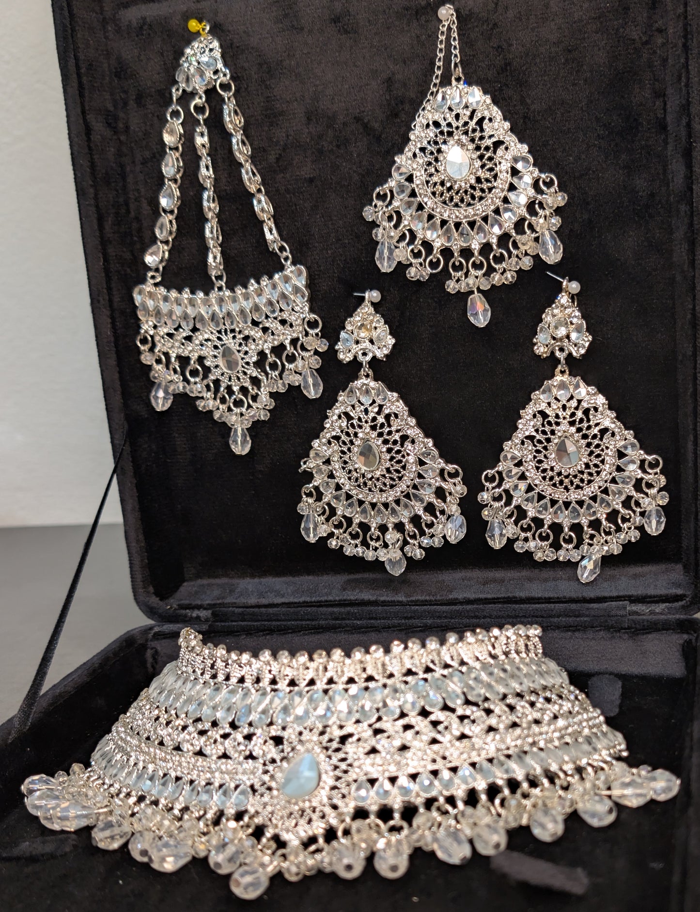 Silver jewelry set including necklace, earrings, and choker on a black background