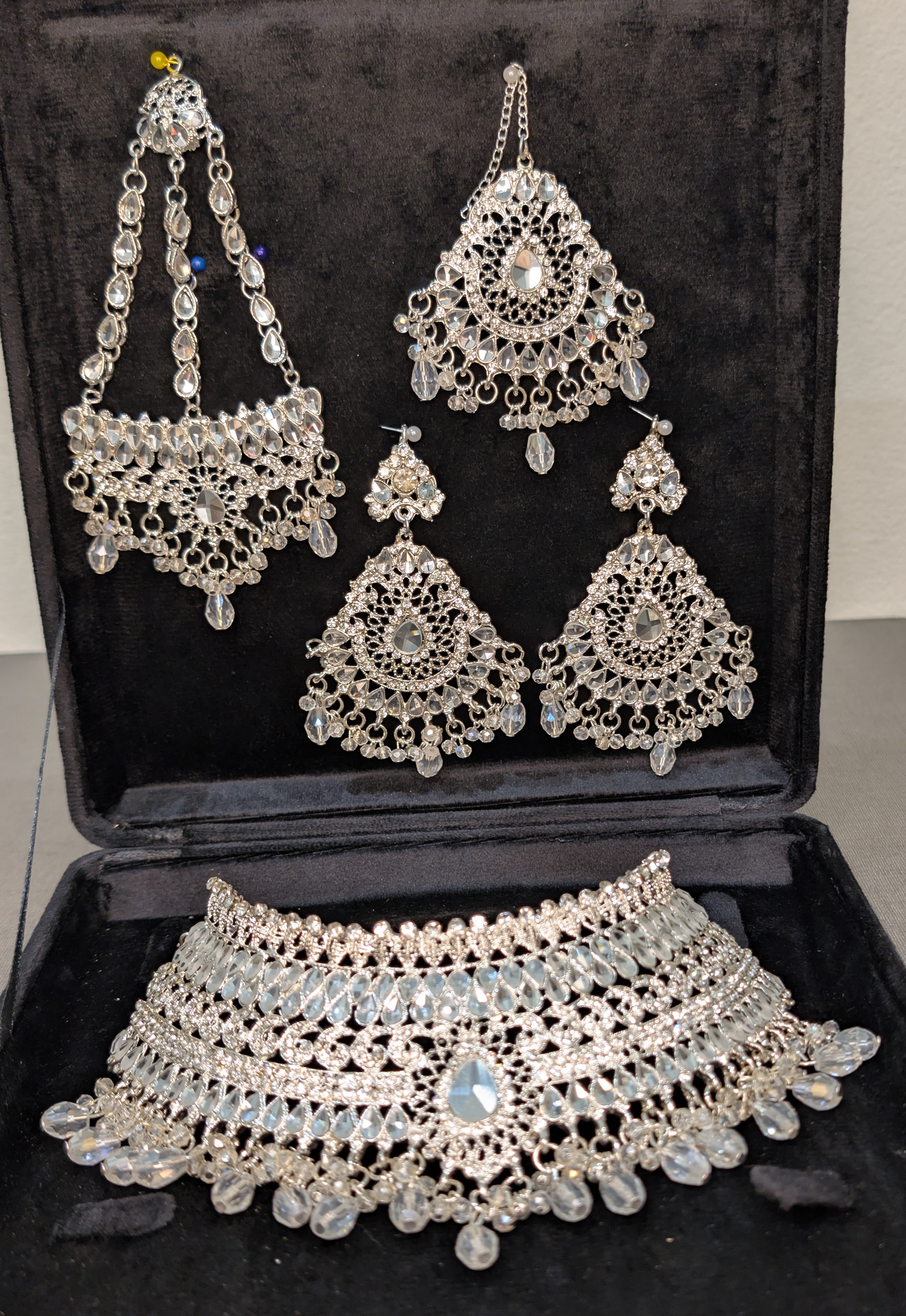 Silver jewelry set including necklace, earrings, and choker on a black background