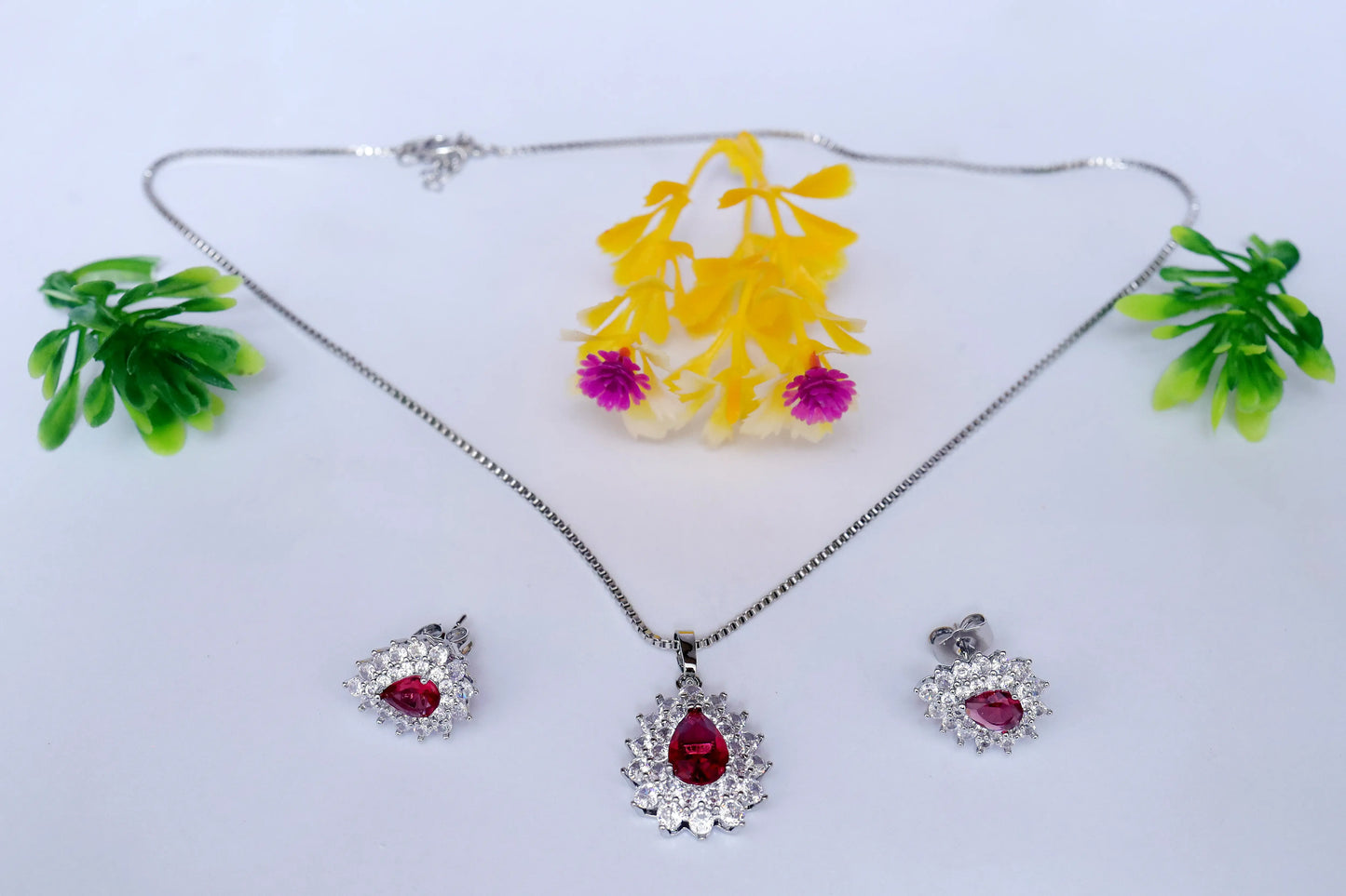 Silver jewelry set with red gemstones on a white background