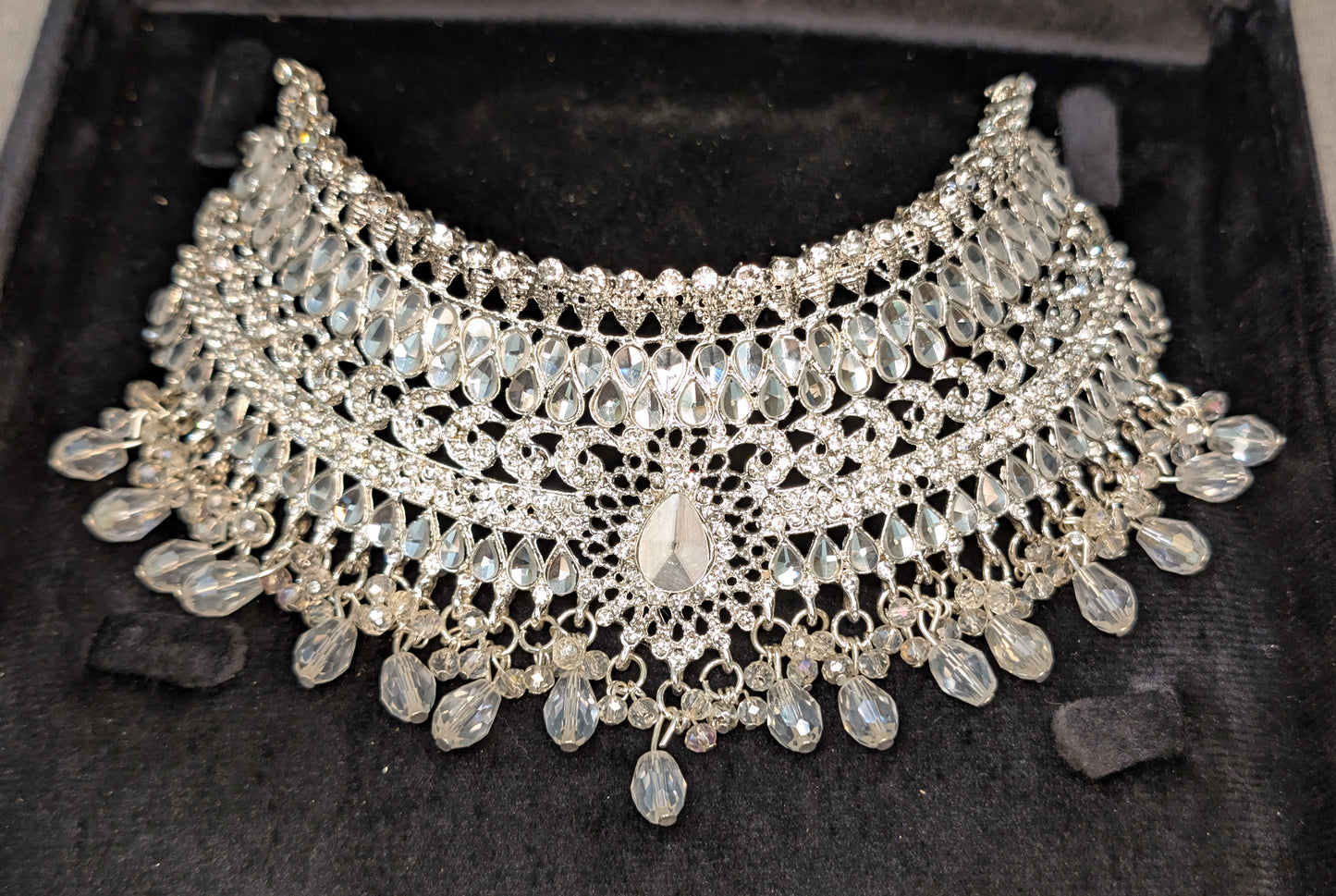 Silver necklace with intricate design on a dark background