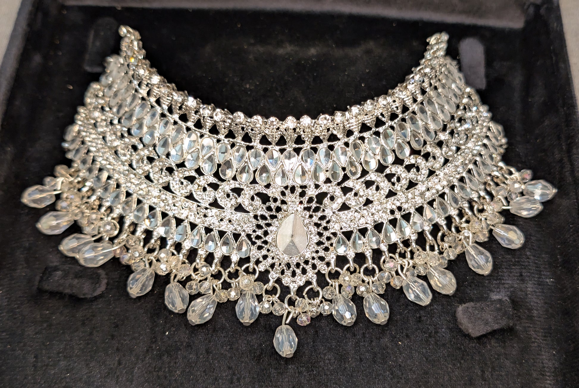 Silver necklace with intricate design on a dark background